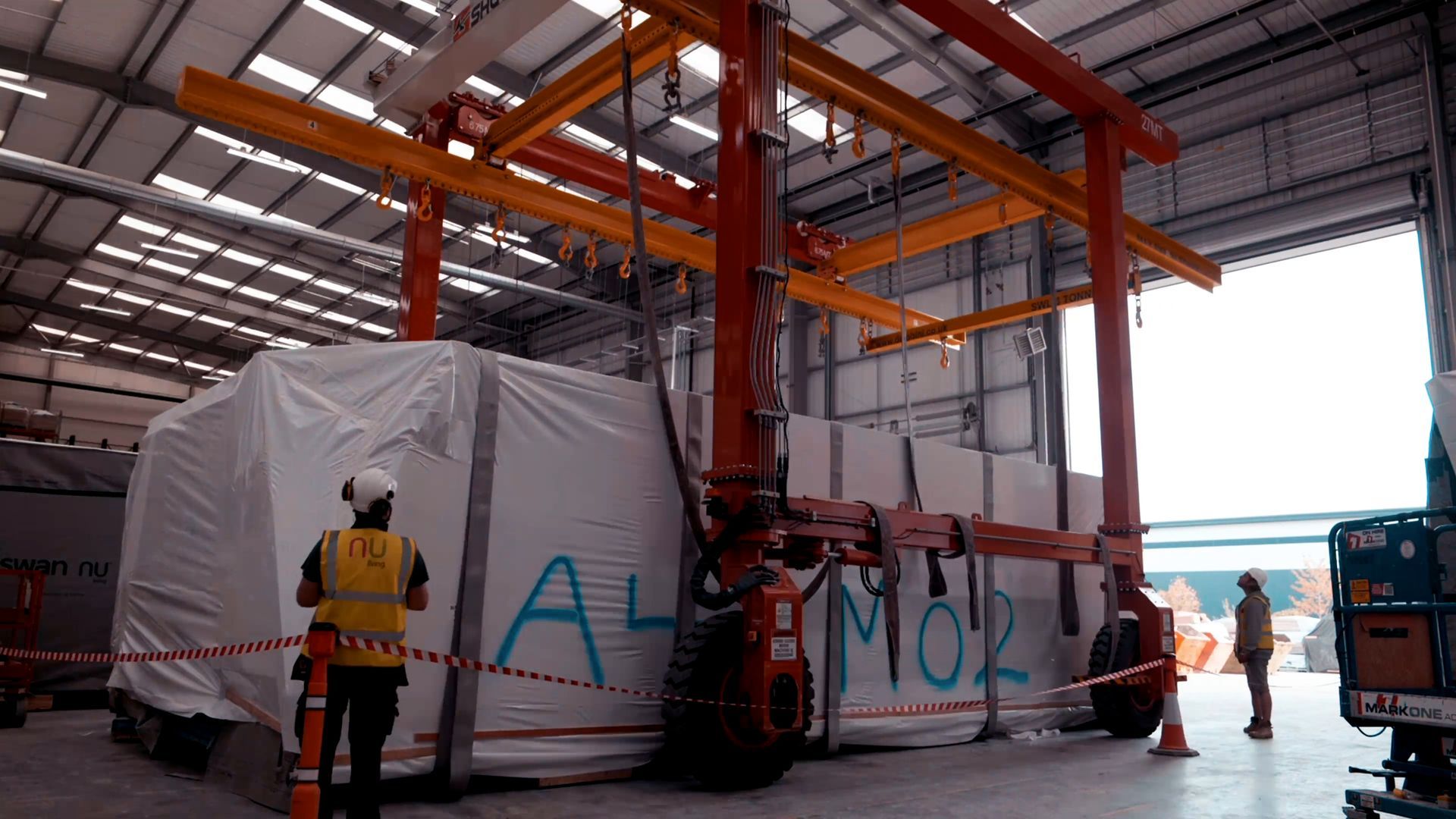 a man in a yellow vest is standing in front of a large container in a warehouse .