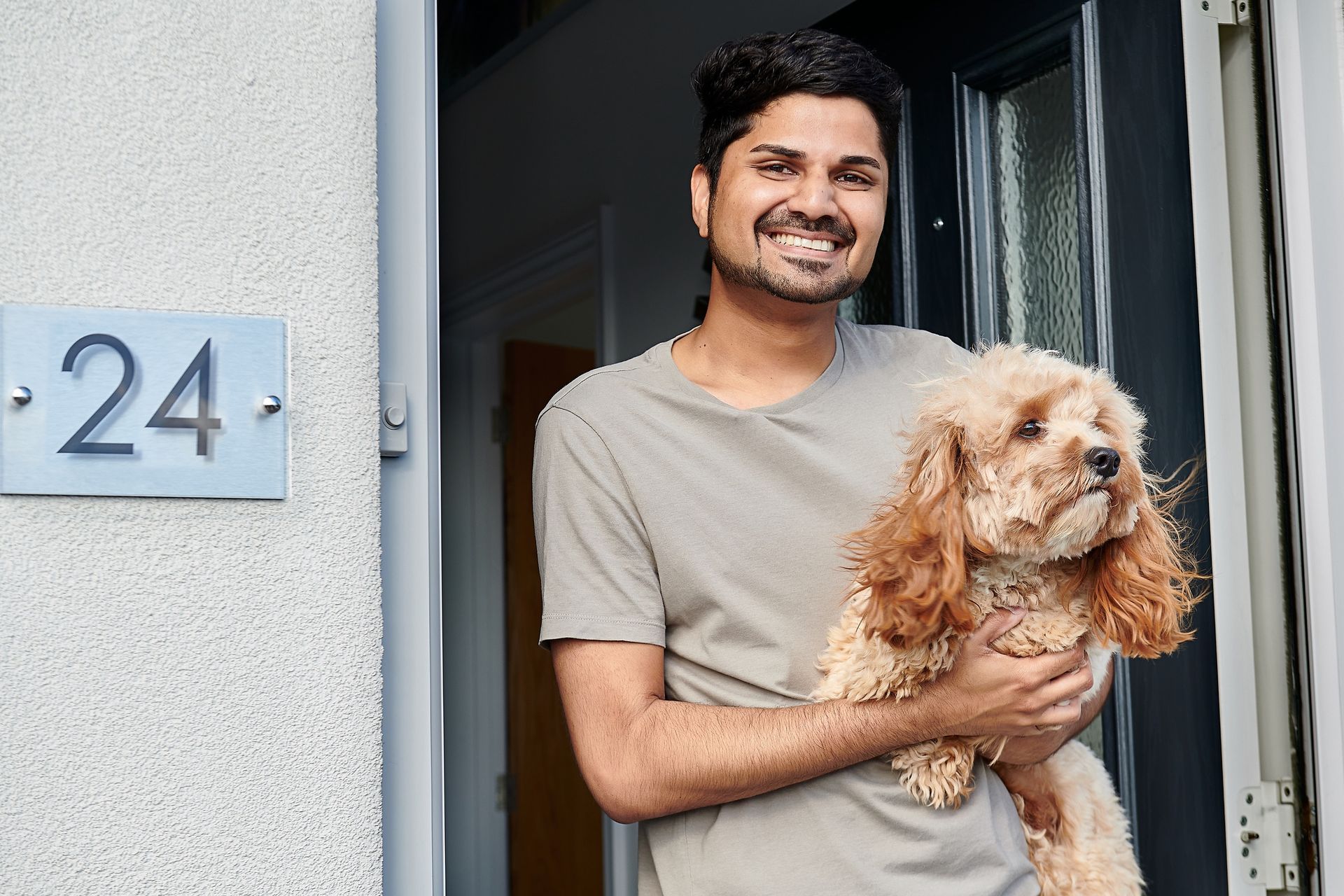 A man is holding a small dog in front of a door.
