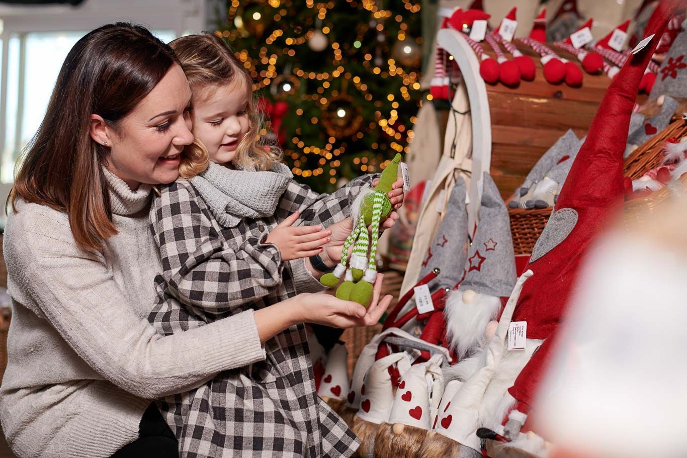A woman and a little girl are sitting in front of a christmas tree.