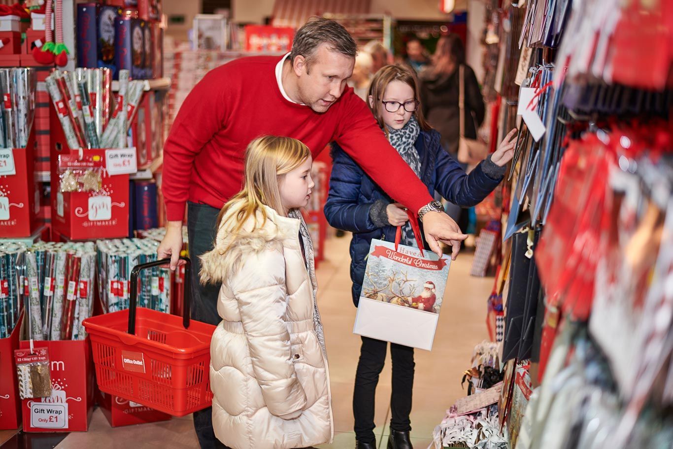A man and two children are shopping for christmas decorations in a store.