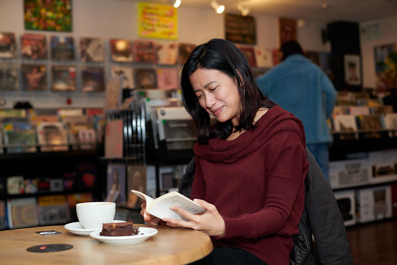 A woman is sitting at a table reading a book.
