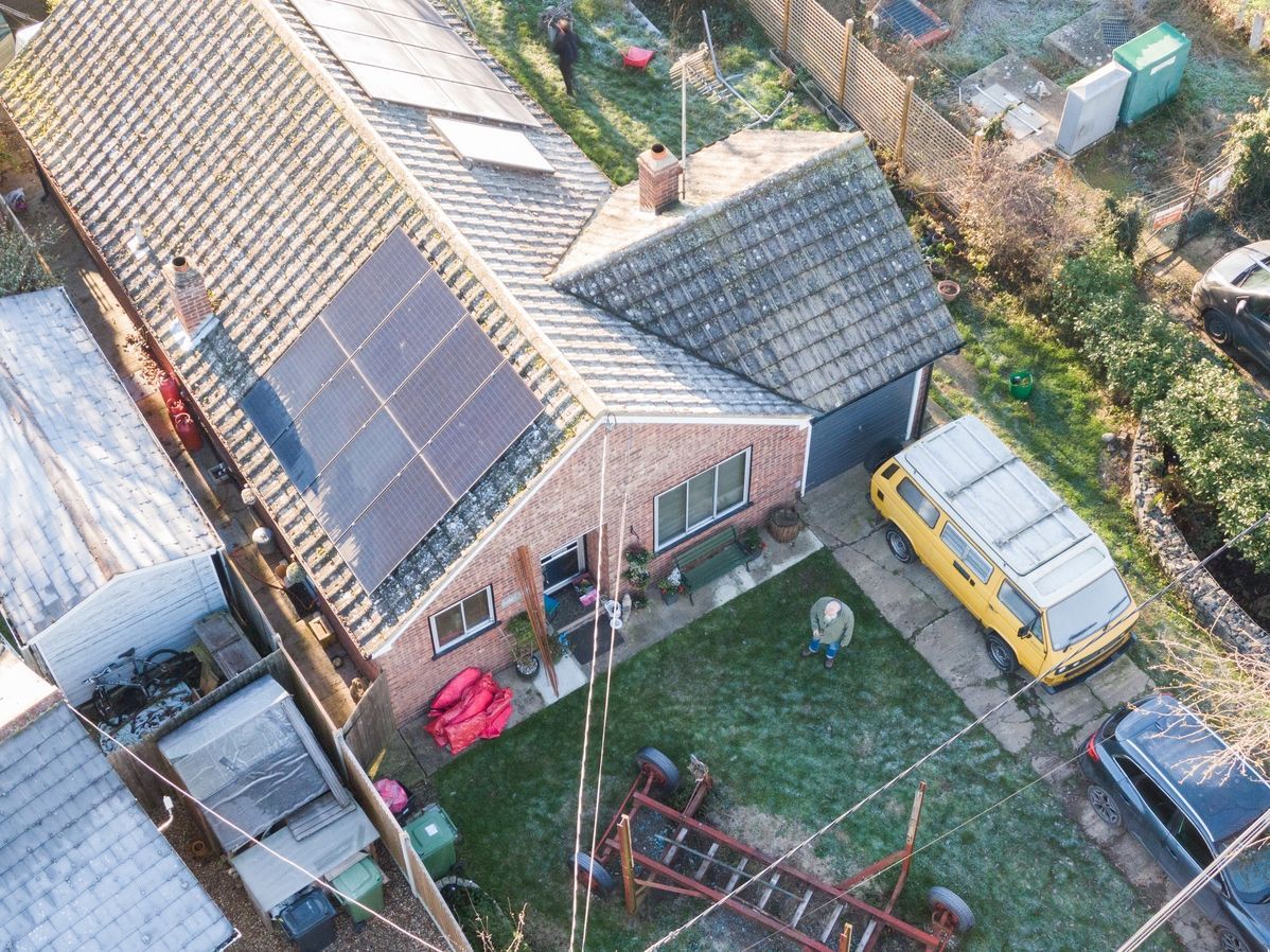 An aerial view of a house with solar panels on the roof.