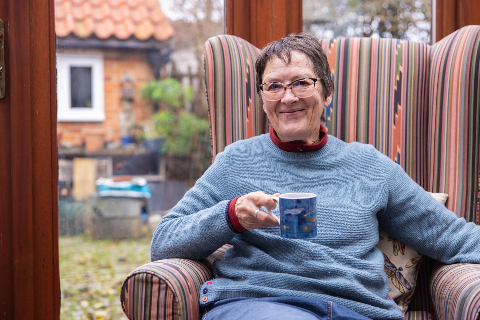 A woman is sitting in a chair holding a cup of coffee.