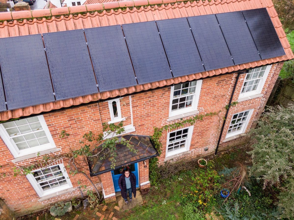 An aerial view of a brick house with solar panels on the roof.