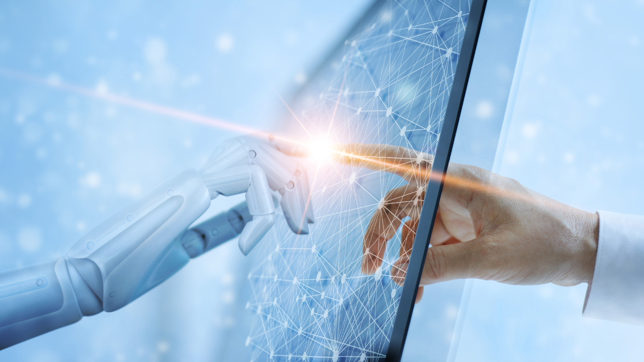 A person is touching a robot 's hand on a computer screen.