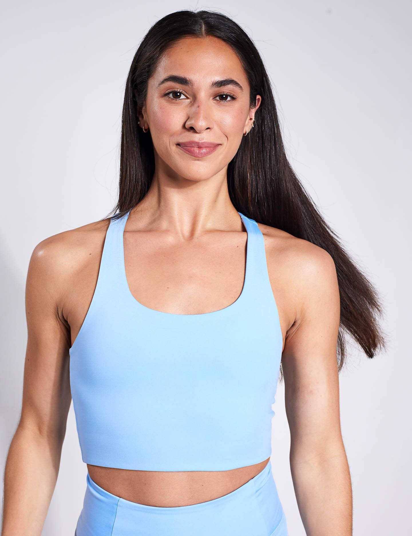 A woman is wearing a light blue sports bra and blue leggings.