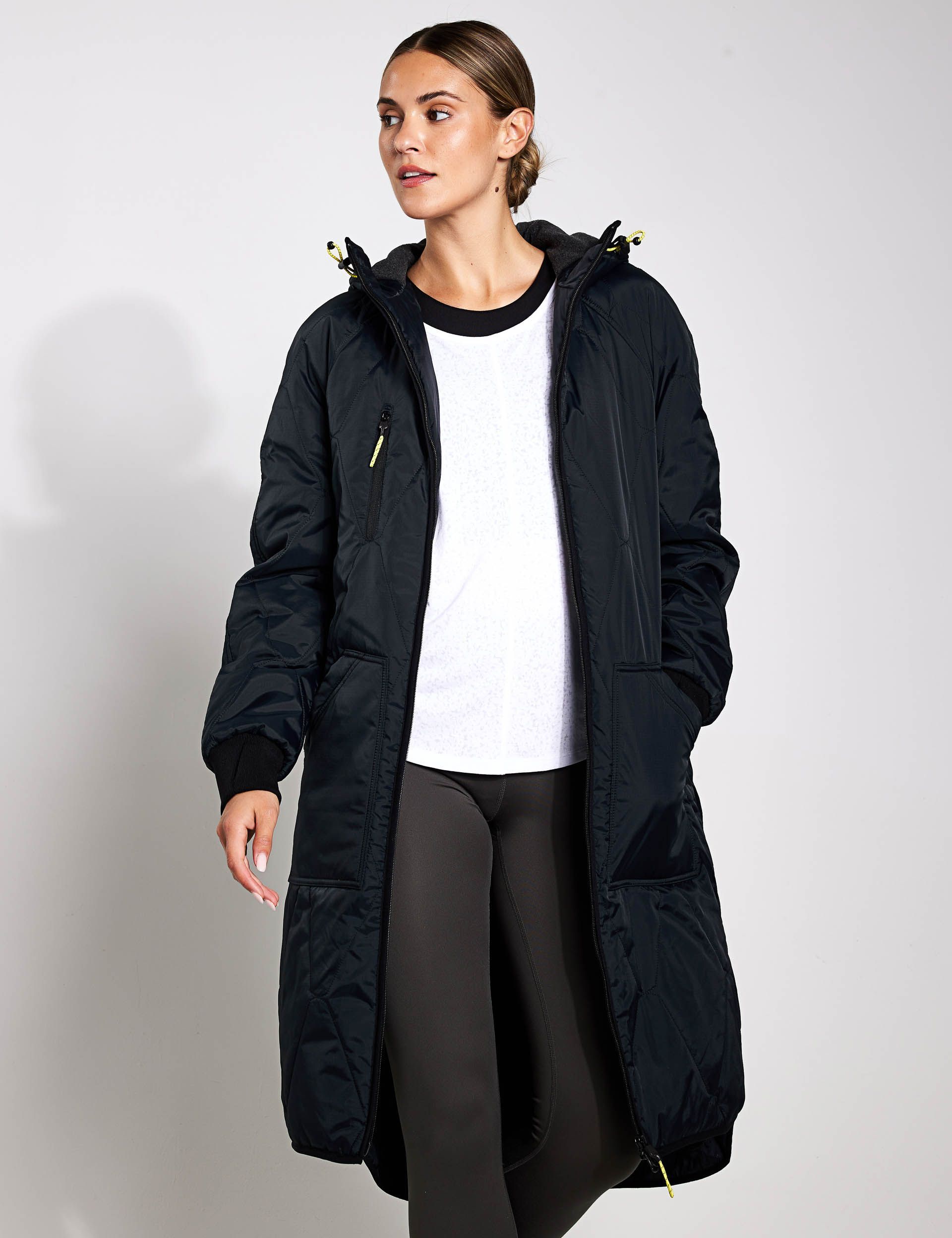 A woman is wearing a black coat and a white shirt.