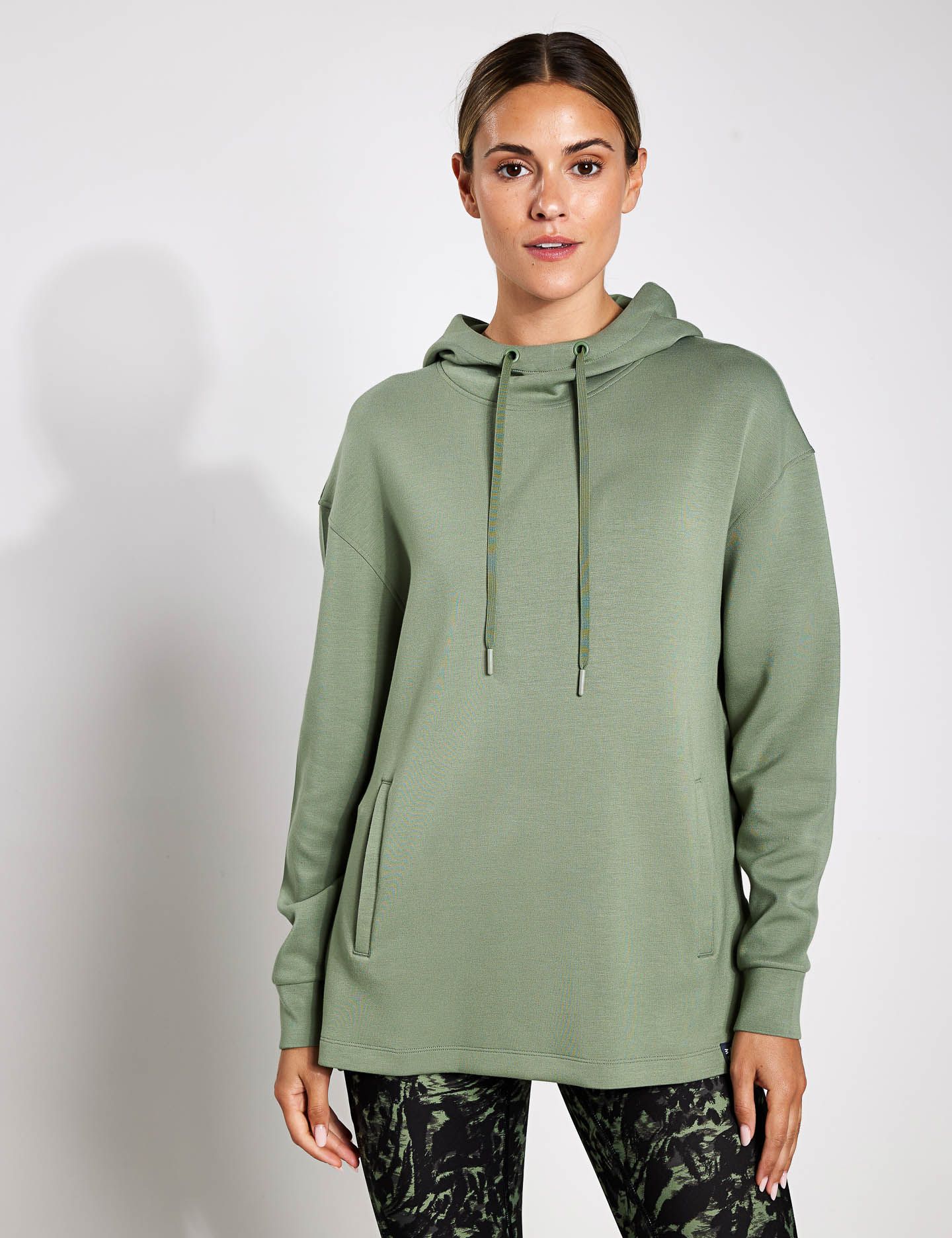 A woman is wearing a green hoodie and black pants.