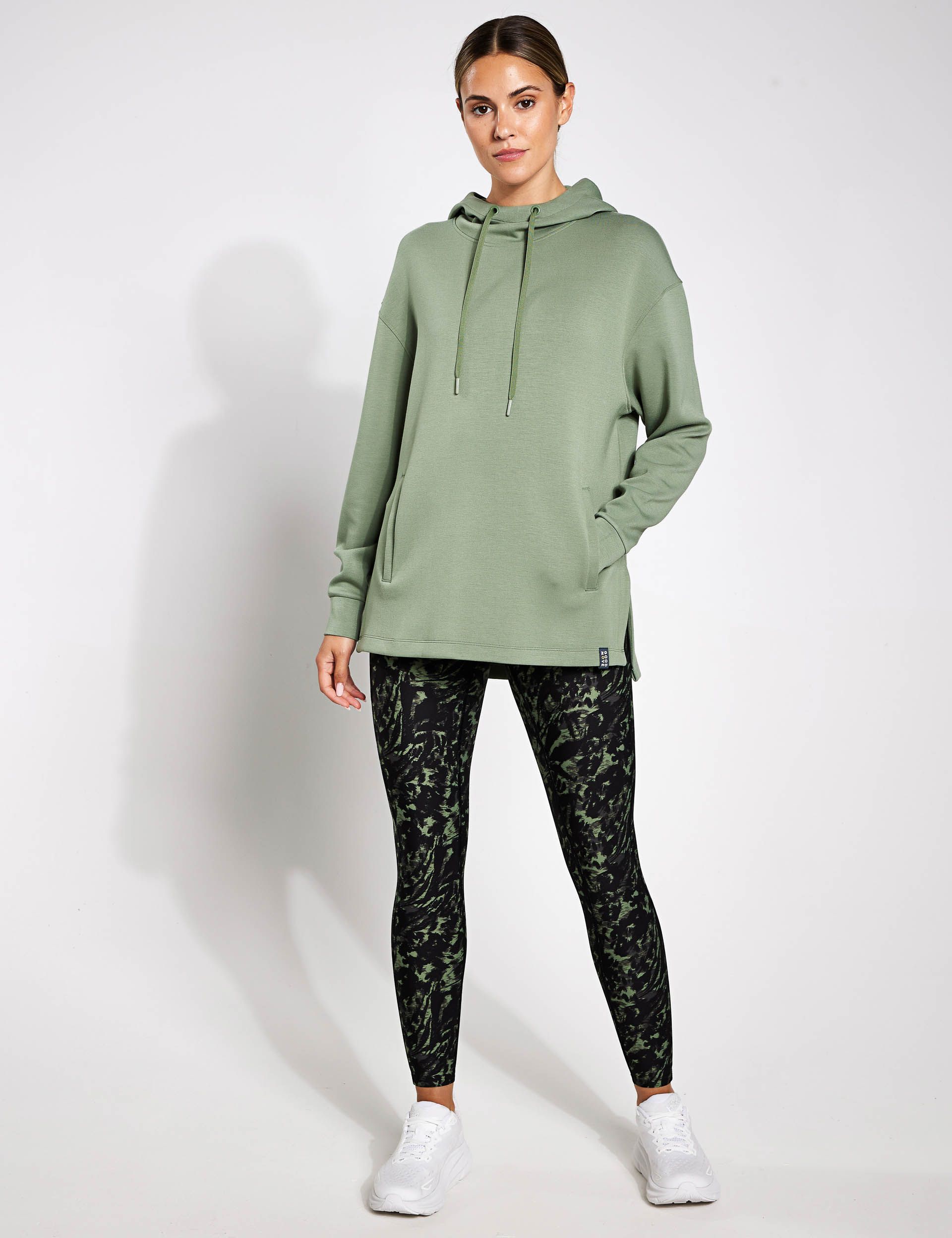 A woman is wearing a green hoodie and black leggings.
