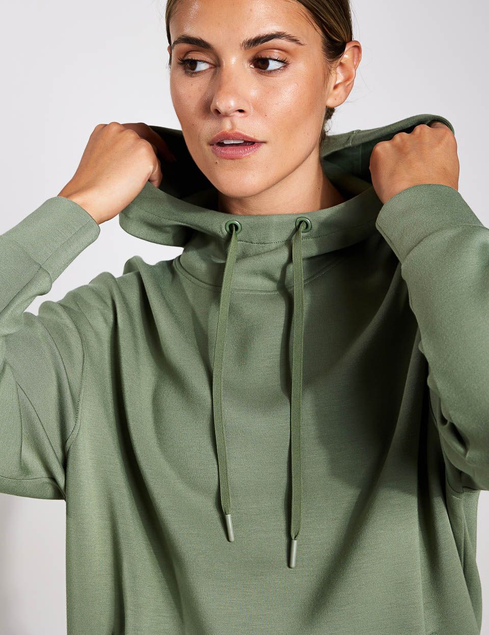 A woman is wearing a green hoodie with a hood