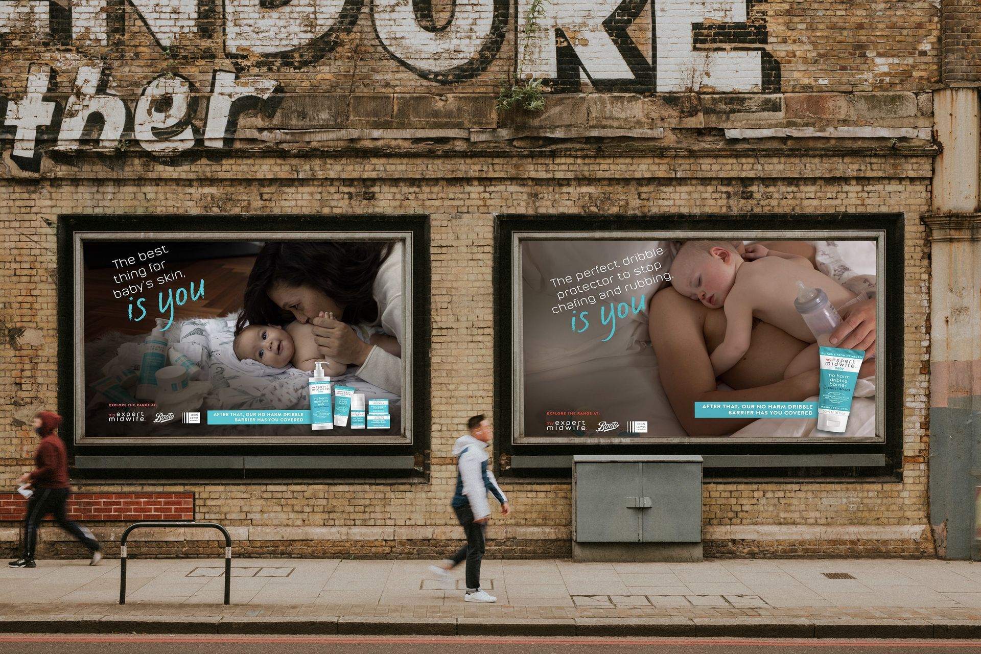 A woman is walking past two billboards on the side of a building.