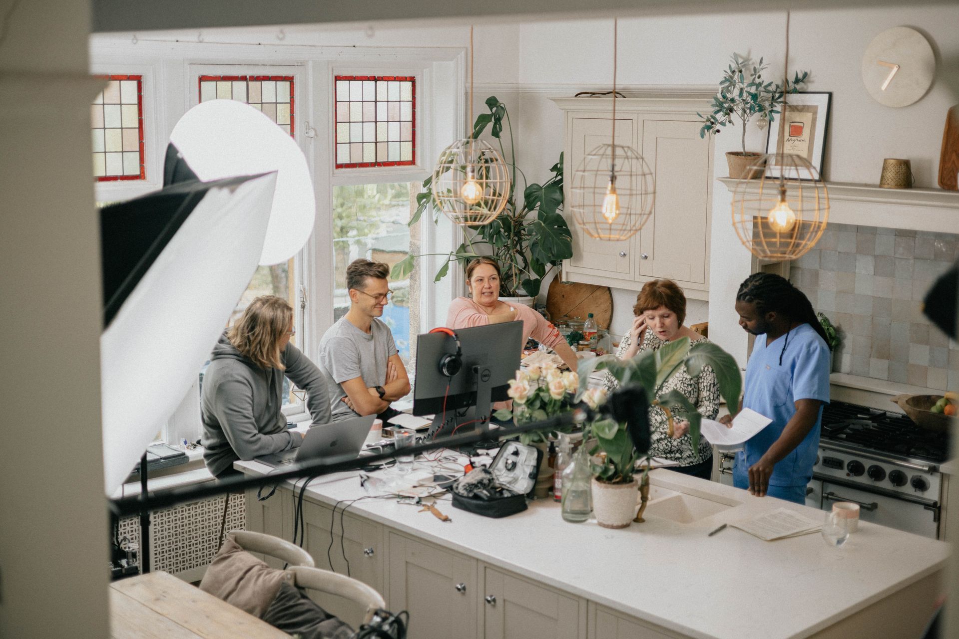 A group of people are standing around a kitchen counter looking at a computer screen.