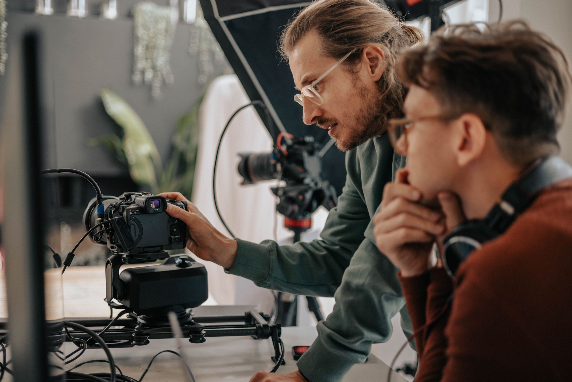 Two men are working on a camera in a studio.