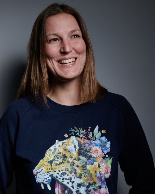 A woman is wearing a blue sweatshirt with a leopard and flowers on it.