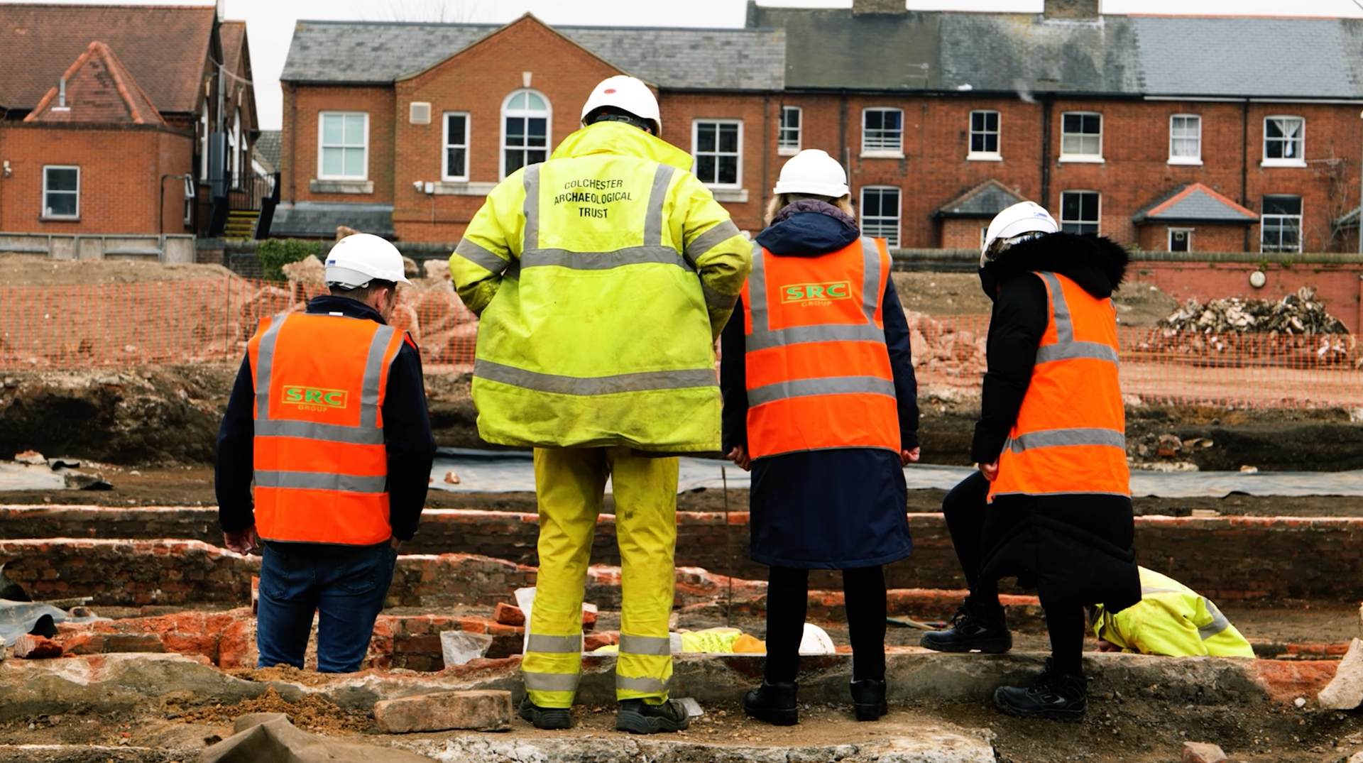A group of construction workers are standing in front of a brick building.