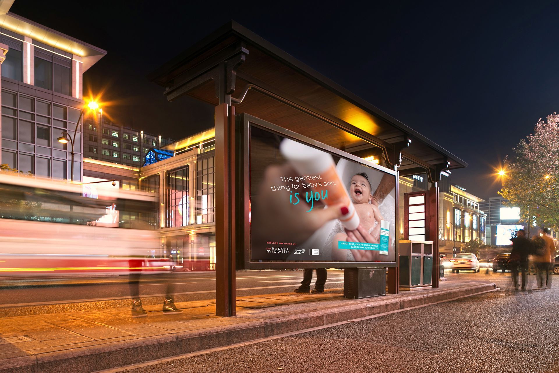 A bus stop with a billboard on it at night.
