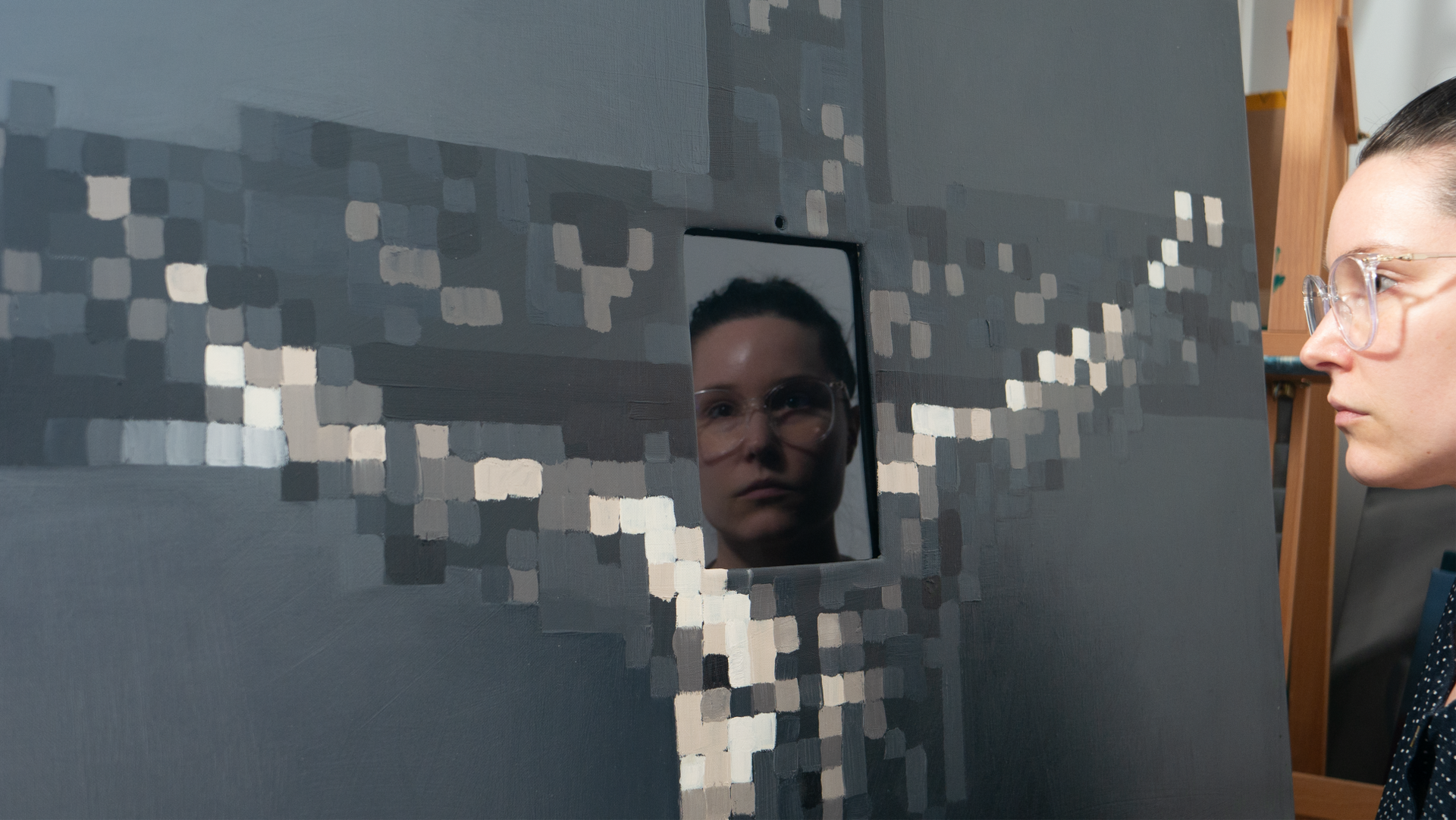 Artist Lala Drona seeing her reflection in black screen of expanded painting Virtual Reverence