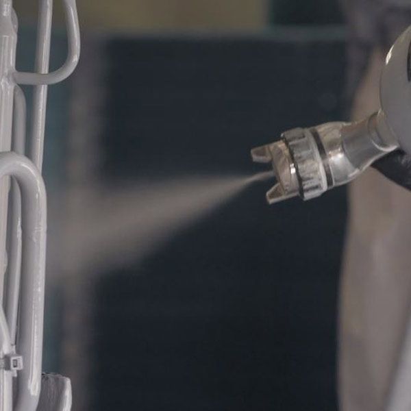Close-up of a metal spray nozzle misting liquid in a gray industrial setting