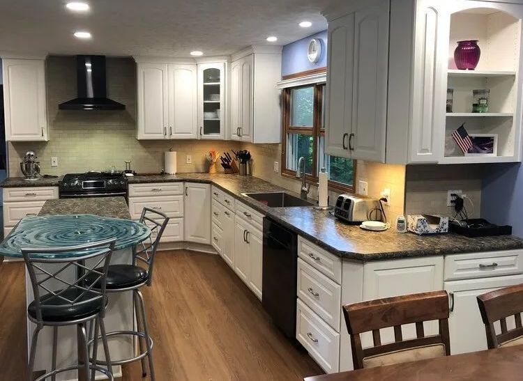 White kitchen with granite countertops, stainless steel appliances, and a blue glass-top island.