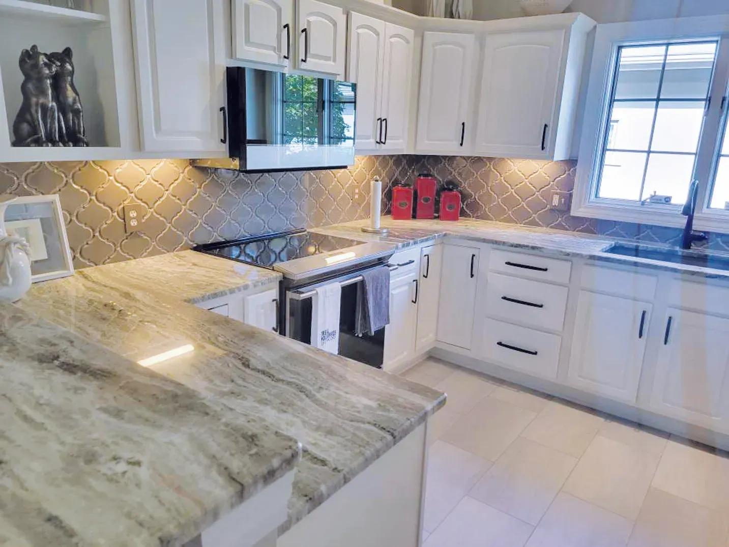 White kitchen with granite countertops, tile backsplash, and stainless steel appliances.