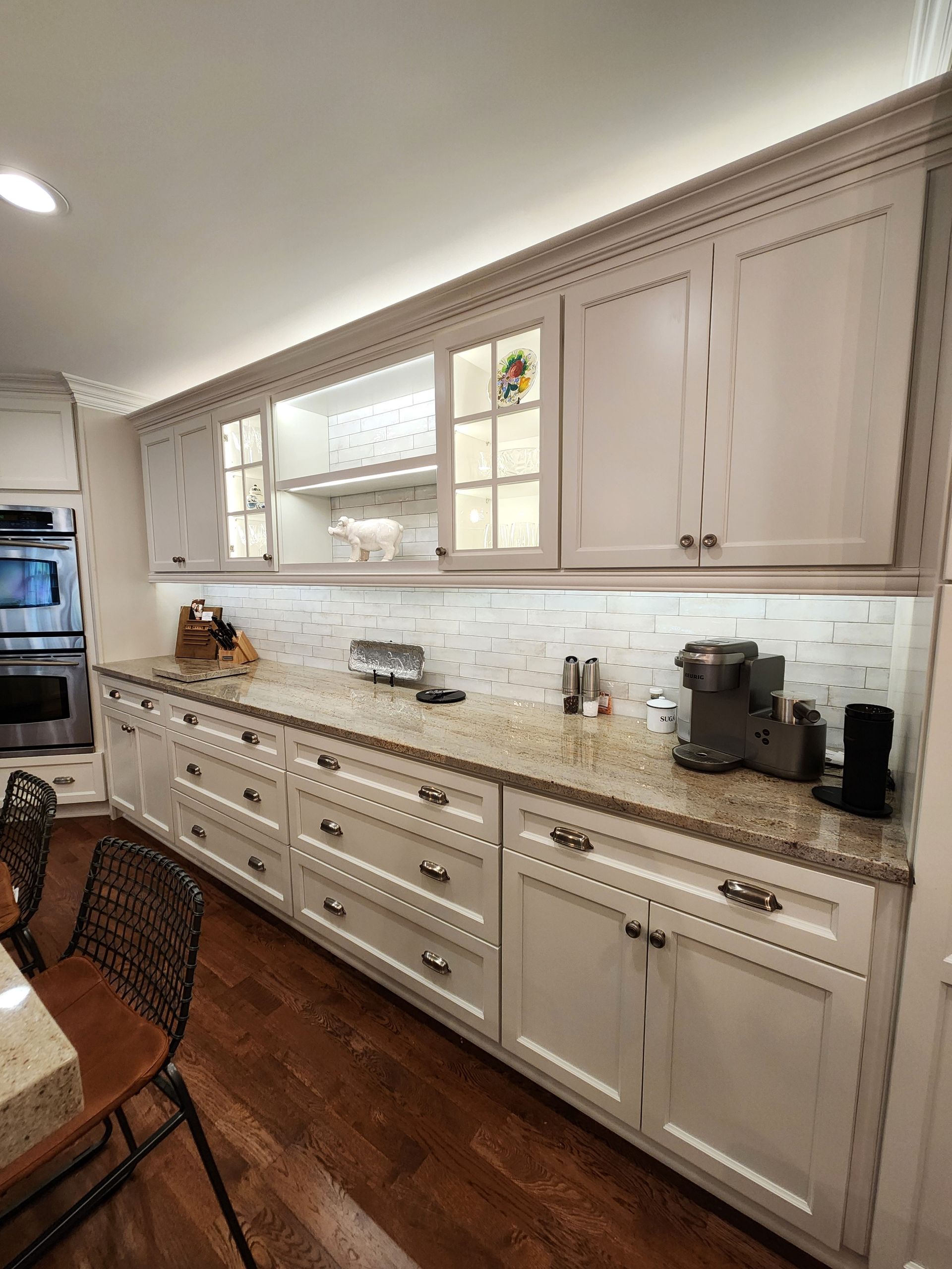 Kitchen with white cabinets, granite countertop, and under-cabinet lighting.