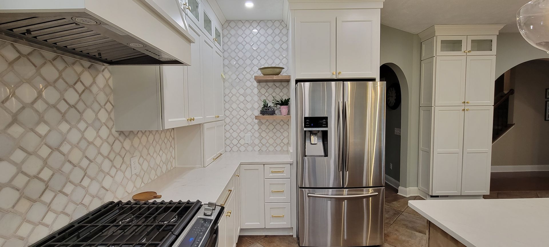 White kitchen with stainless steel appliances, white cabinets, and patterned backsplash.