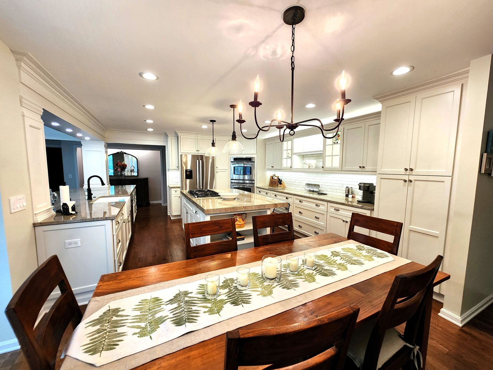 Spacious open-concept kitchen and dining area with wood table, white cabinets, and stainless steel appliances.