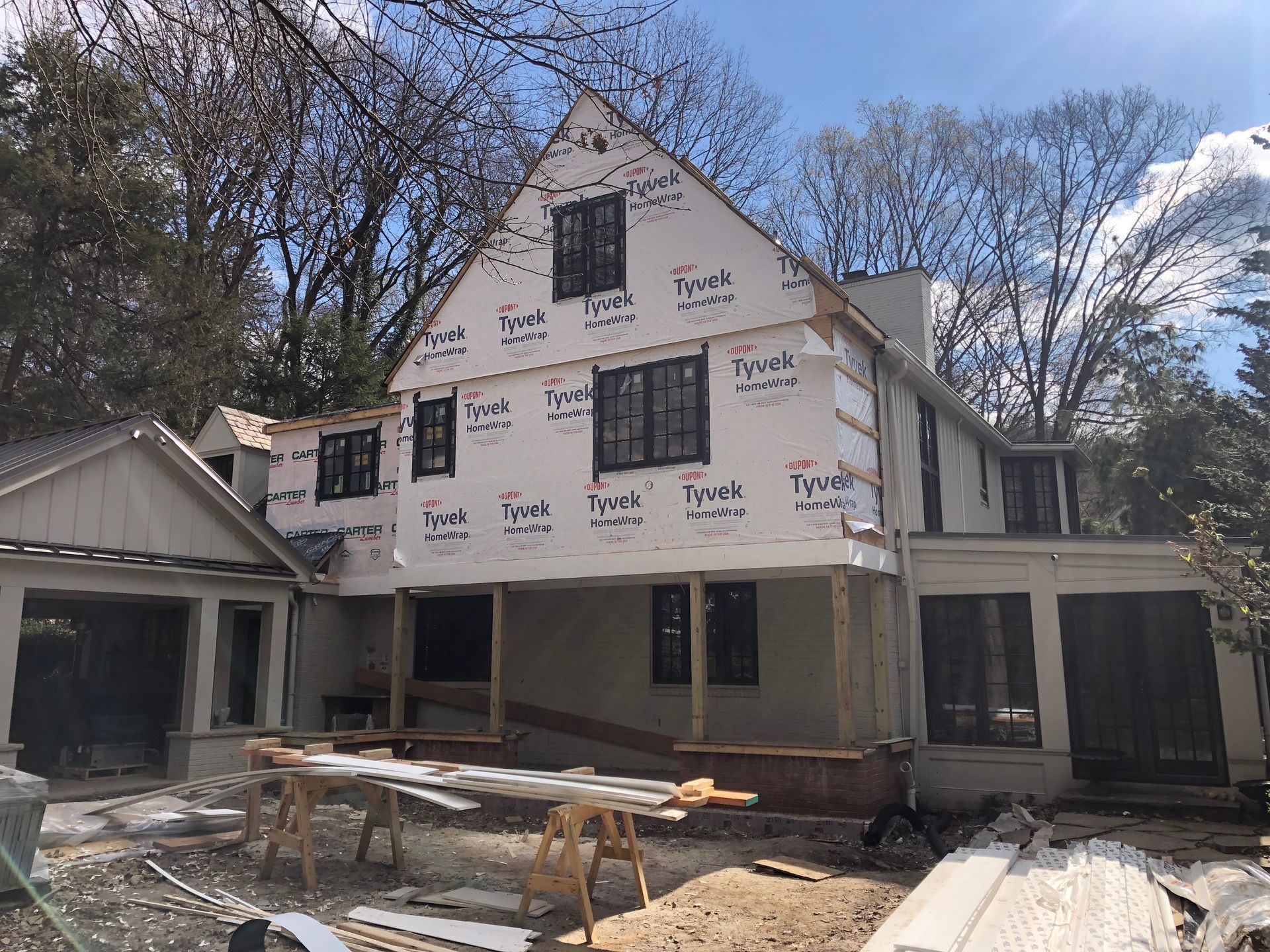 House under construction, covered in Tyvek wrap, with black window frames.