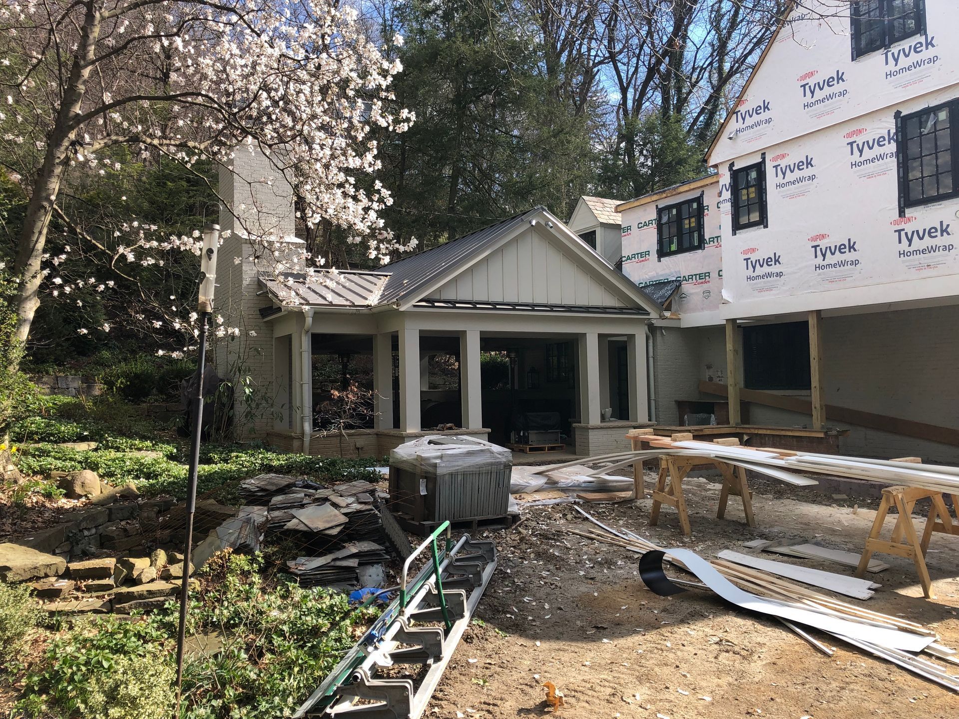 House under construction with a sunroom, exposed framing, and landscape.
