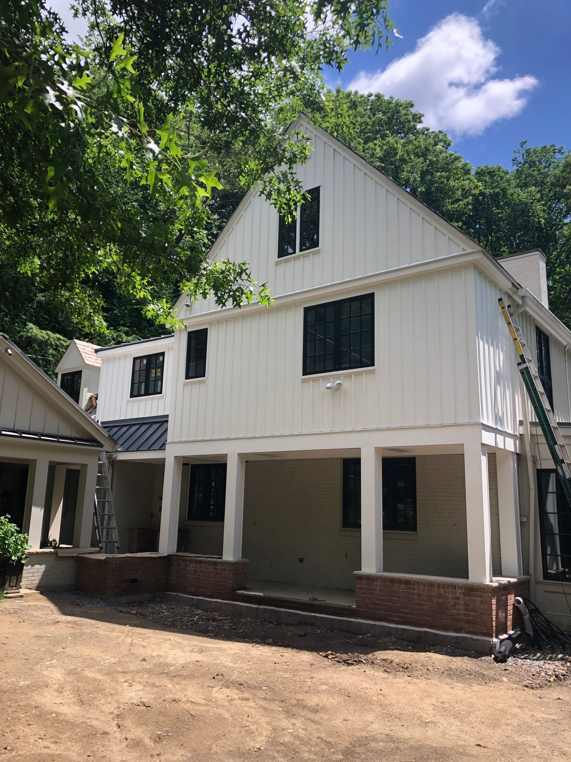 White house under construction with black windows and brick accents.