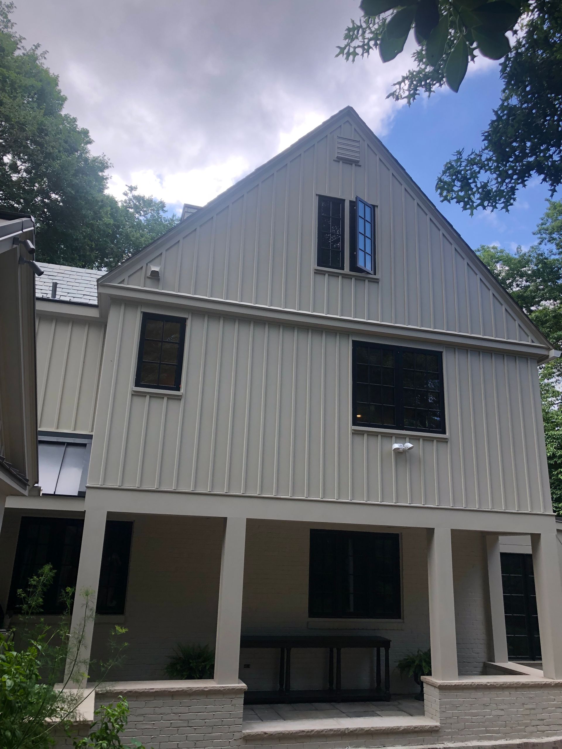 Two-story light gray house with dark windows and a covered porch.