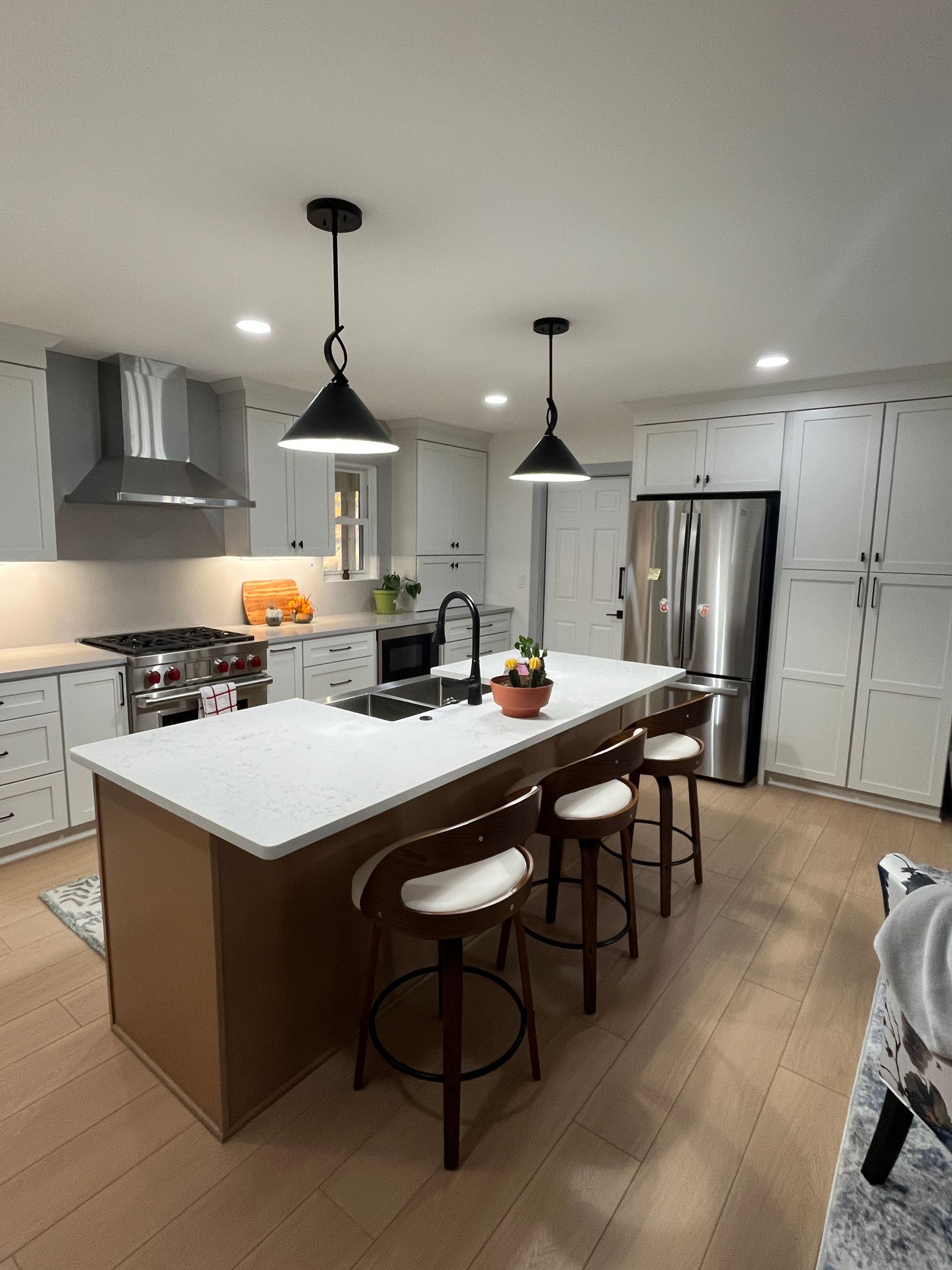 Modern kitchen with white cabinets, stainless steel appliances, and a brown island with stools.