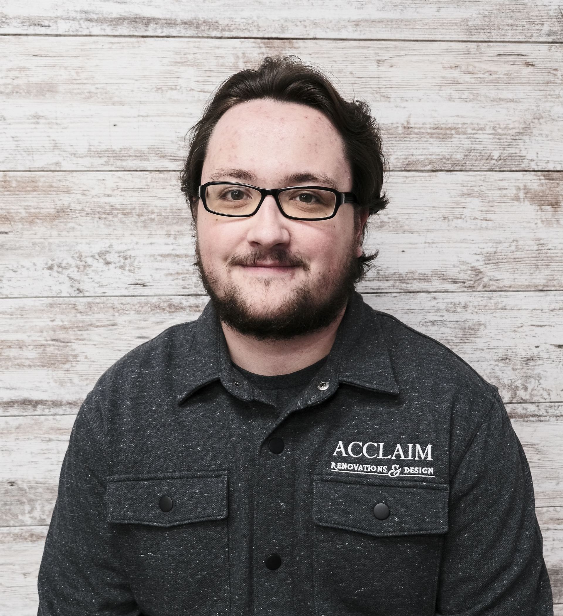 Man with glasses and a beard wearing a dark gray shirt with 