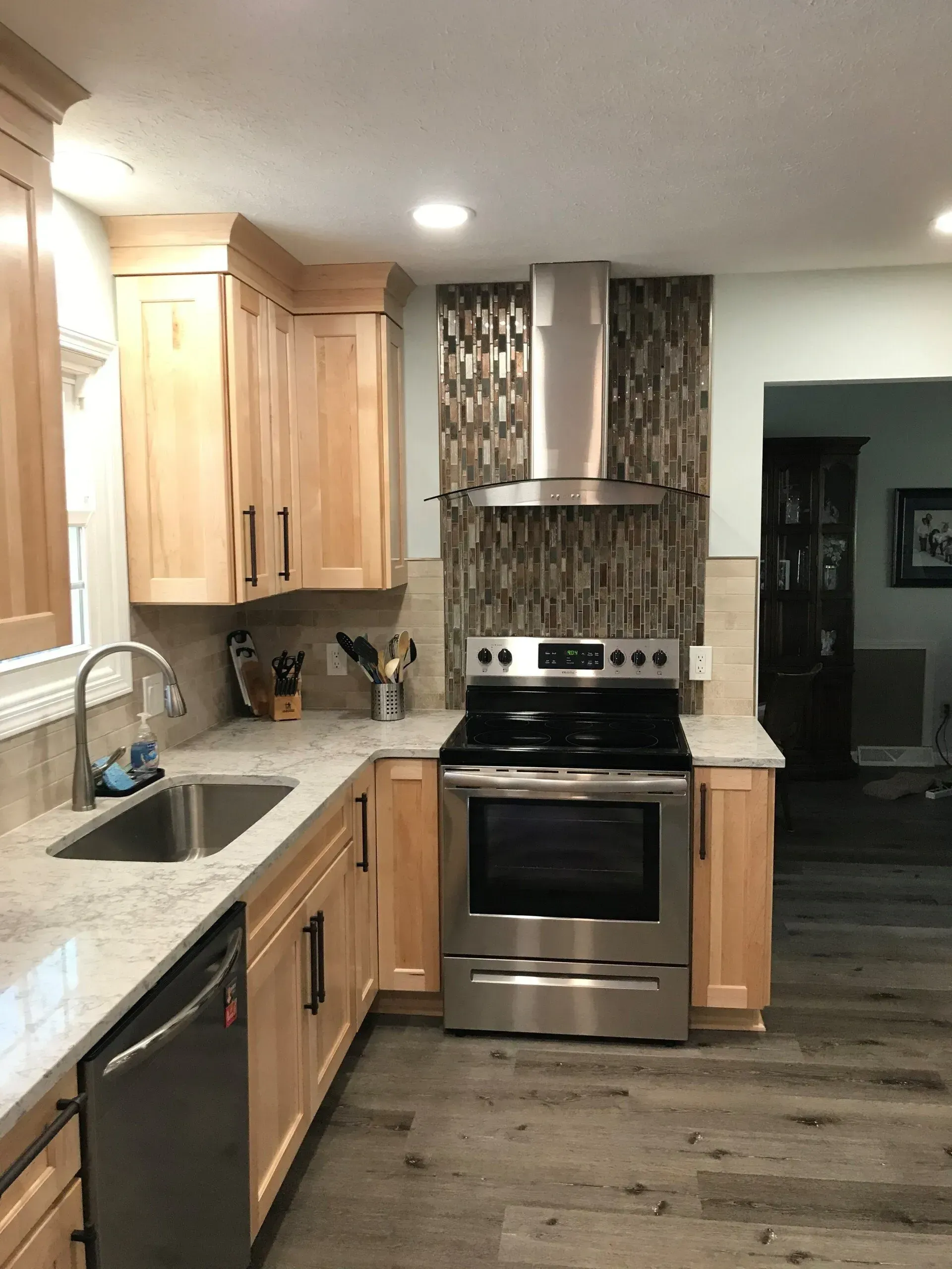 Kitchen with light wood cabinets, stainless steel appliances, and tile backsplash.