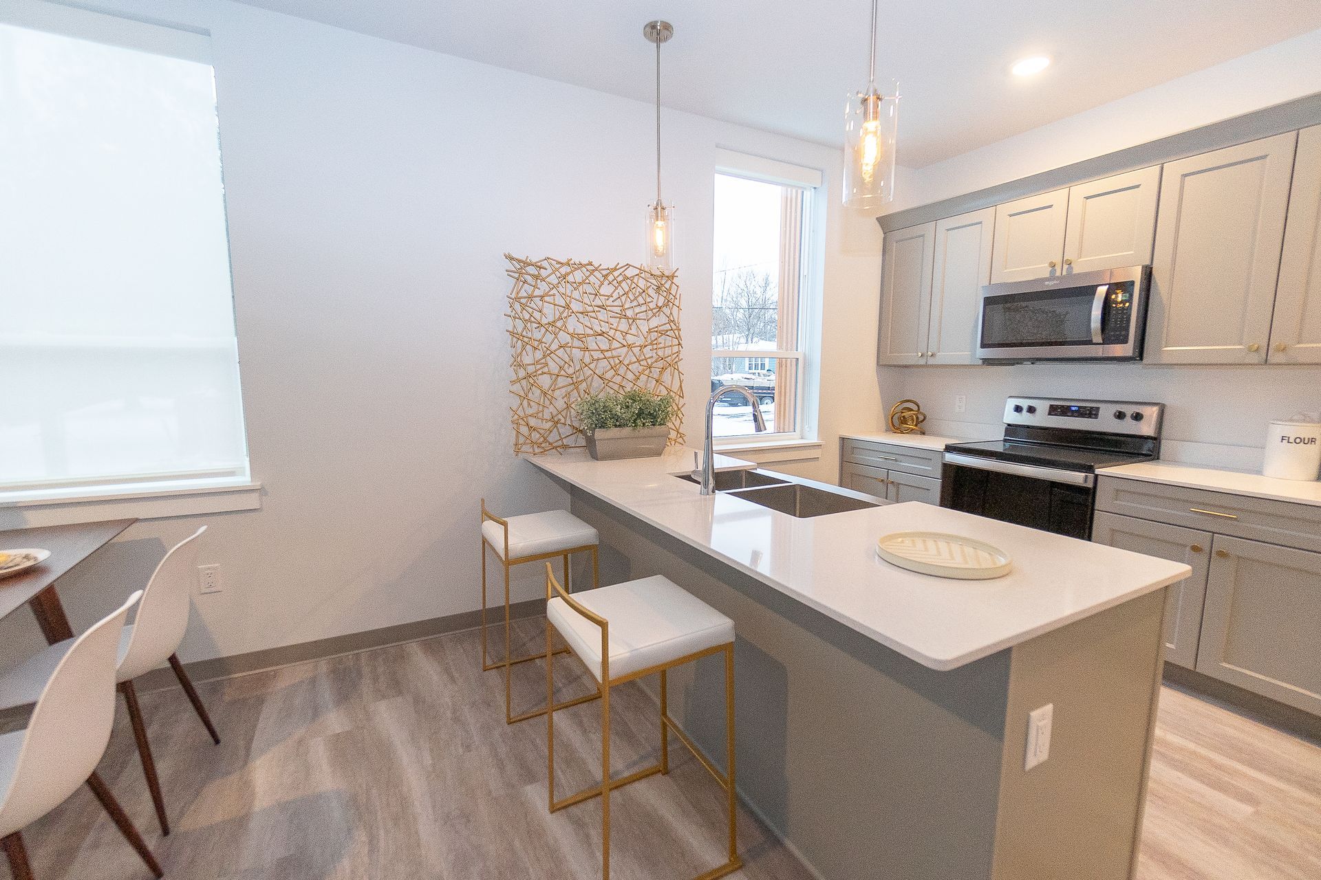 A kitchen with a large island , stools , a stove and a microwave.