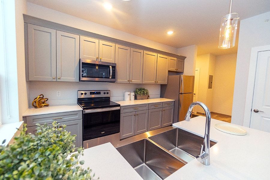 A kitchen with a sink , stove , refrigerator and microwave.