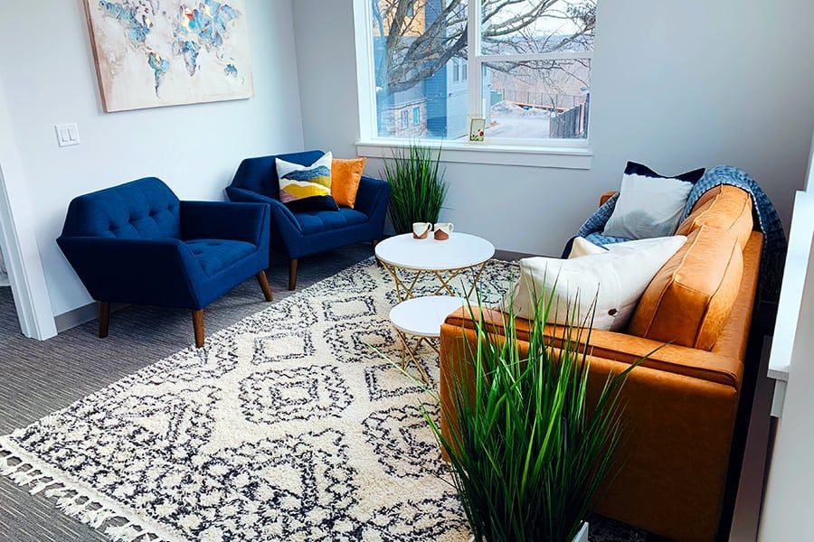 A living room with a couch , chairs , and a rug.