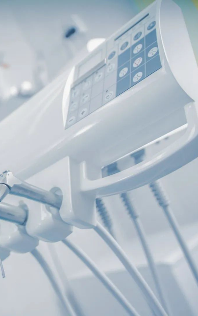 Primo piano di un monitor medico ospedaliero con cavi in un ambiente clinico luminoso.