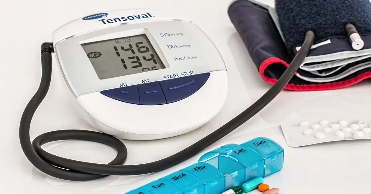 Blood pressure monitor with cuff, stethoscope, and pills on a white surface