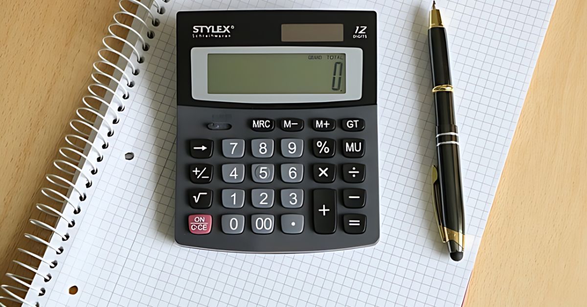 Calculator, notebook, and black pen on a desk.