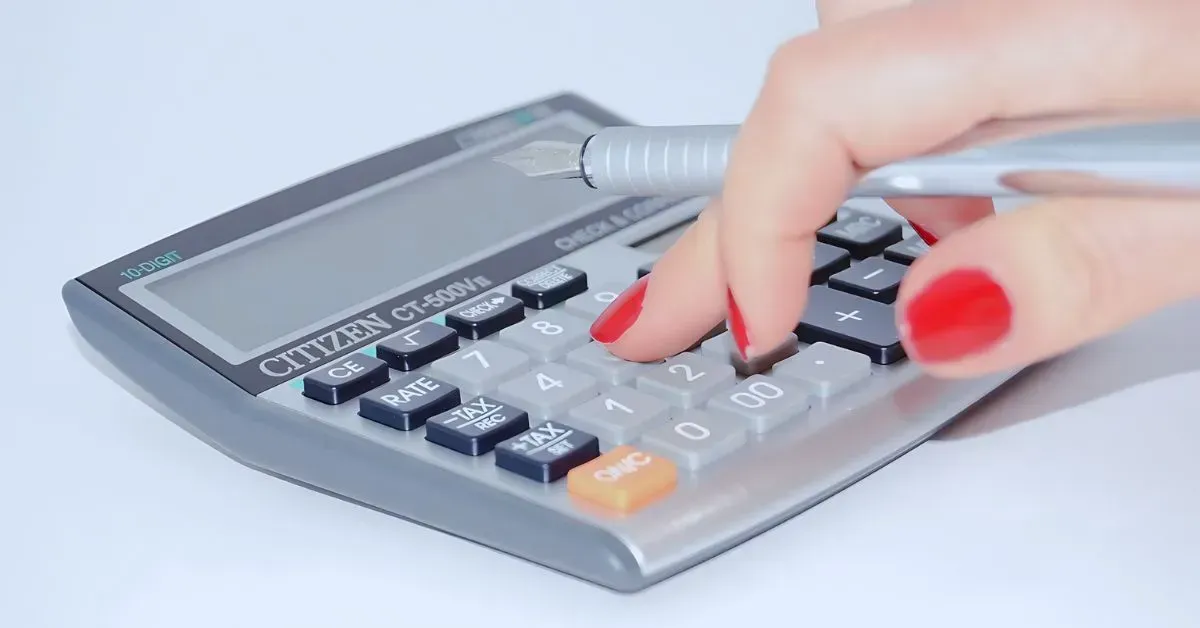 Hand pressing buttons on a gray calculator with a dark display