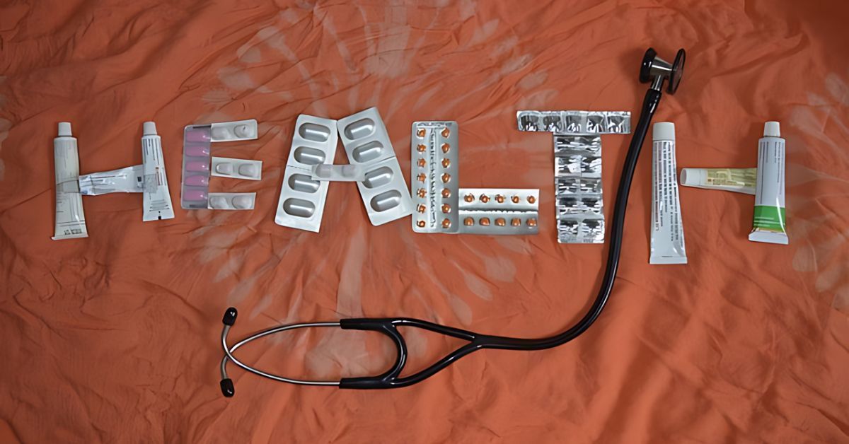 “H E A L T H” spelled with pill packages on an orange cloth, with a stethoscope below