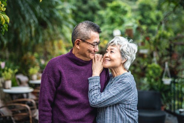 Two people smiling in a lush garden, leaning close in a tender moment