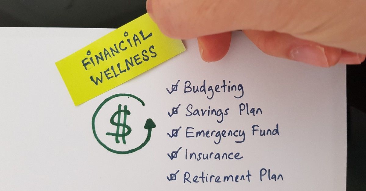 Hand placing a yellow “Financial Wellness” note beside a checklist