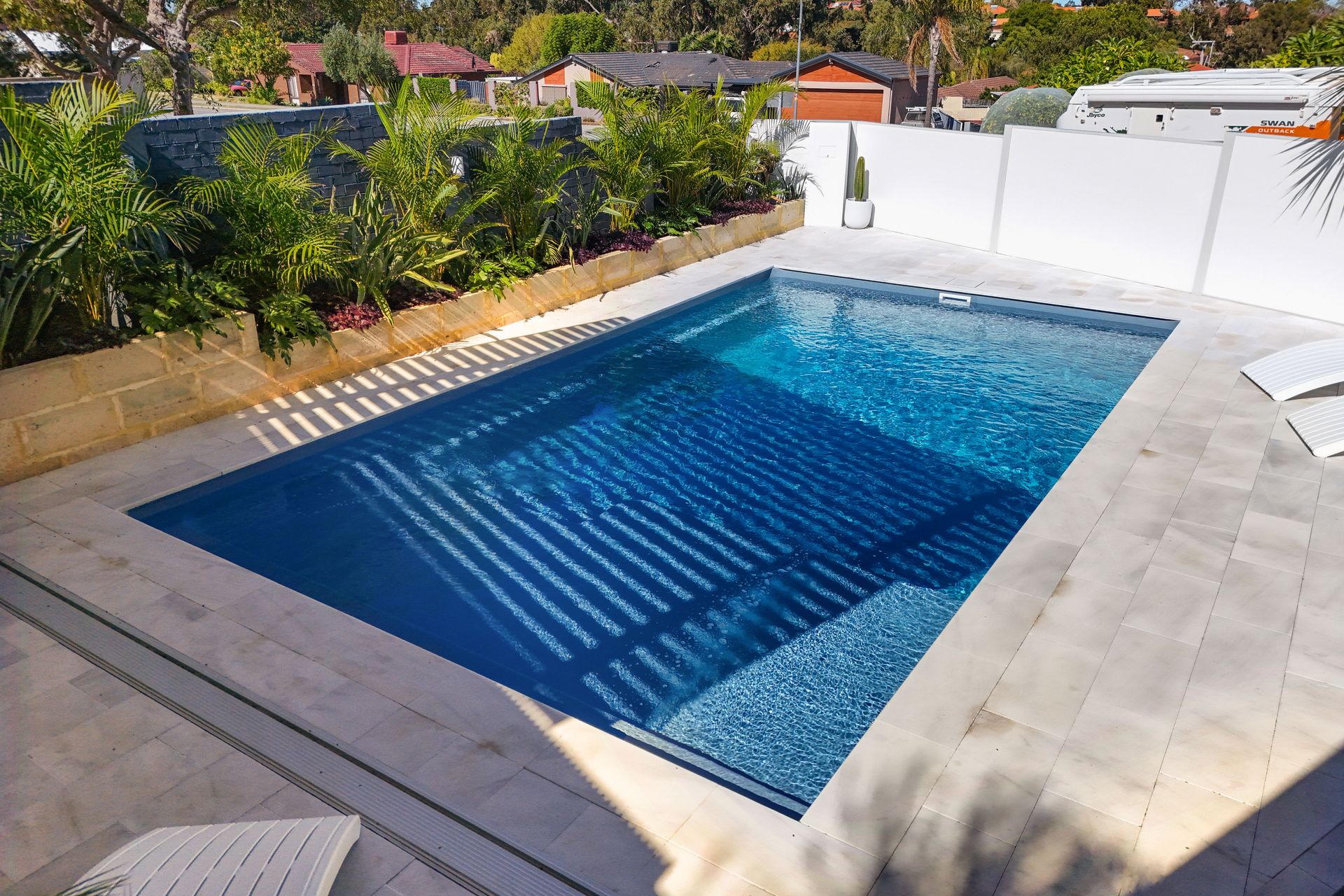 A Large Swimming Pool With Chairs And Umbrellas Around It — Gibson Family Pools Pty Ltd In Port Macquarie, NSW