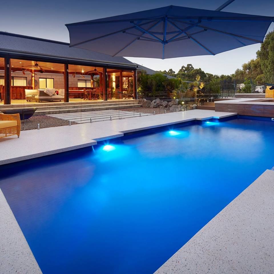 A Large Swimming Pool With a House in the Background — Gibson Family Pools Pty Ltd In Laurieton, NSW