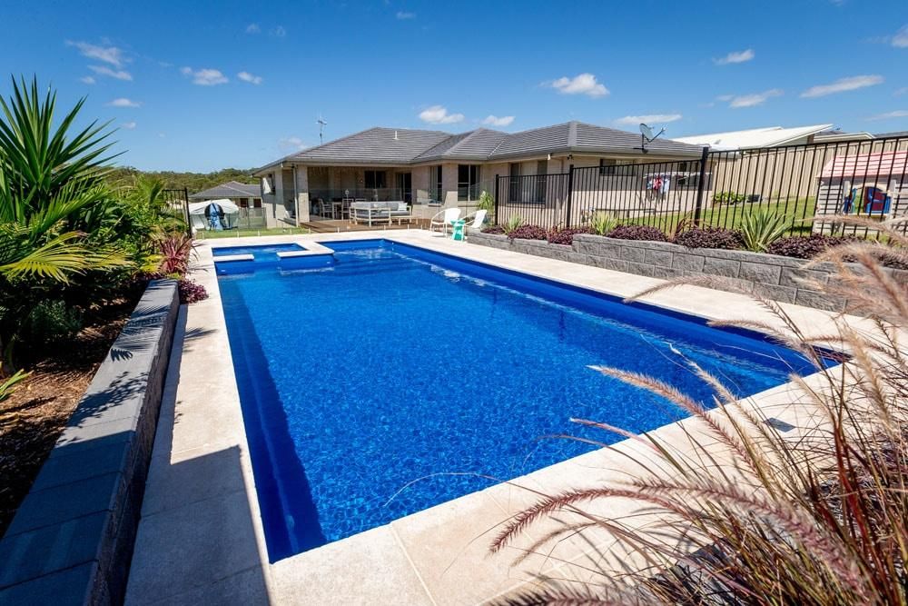 A Large Swimming Pool is in the Backyard of a House — Gibson Family Pools Pty Ltd In Kempsey, NSW