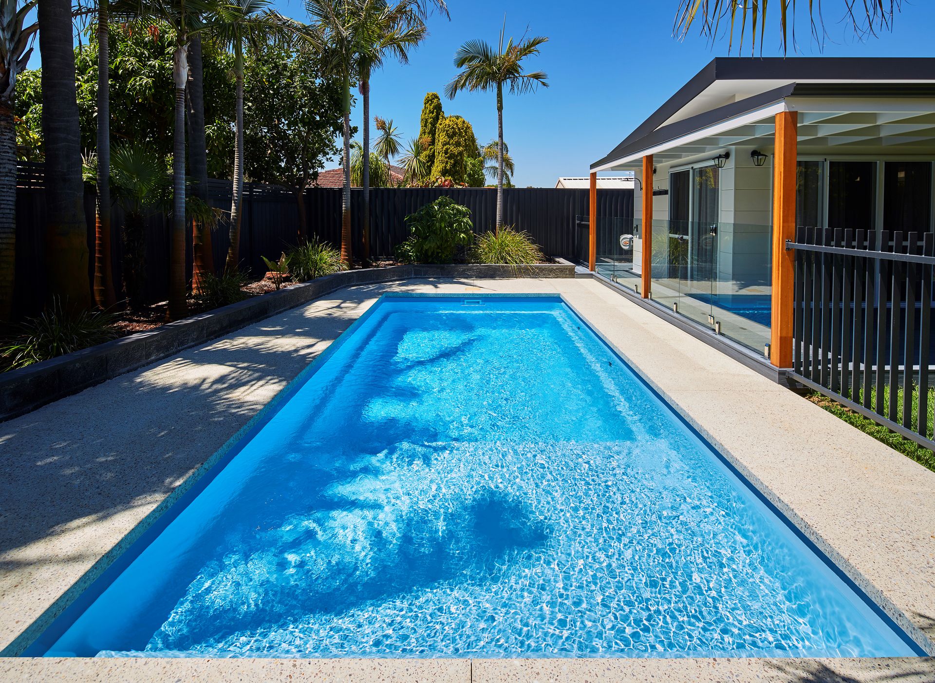 A Large Black Swimming Pool is Lit Up at Night — Gibson Family Pools Pty Ltd In Wauchope, NSW