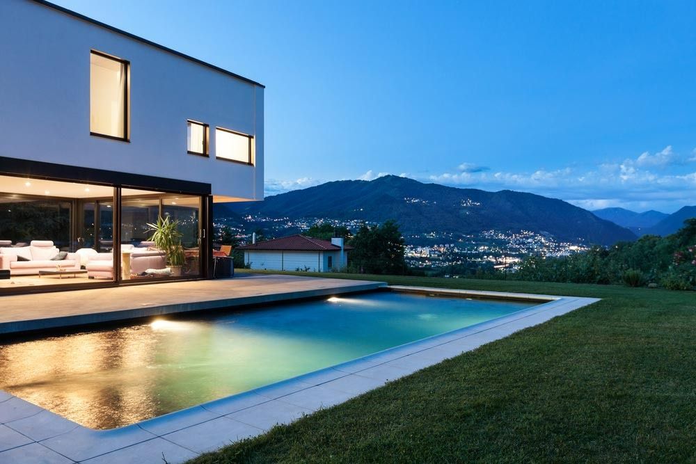 A Modern House With A Large Swimming Pool In Front Of It — Gibson Family Pools Pty Ltd In Port Macquarie, NSW