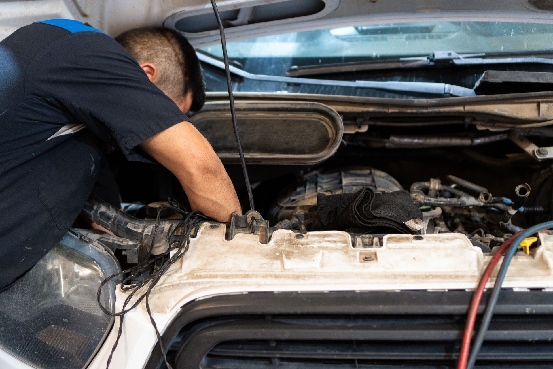 Mechanic working on the engine of a vehicle, in a well-lit garage.